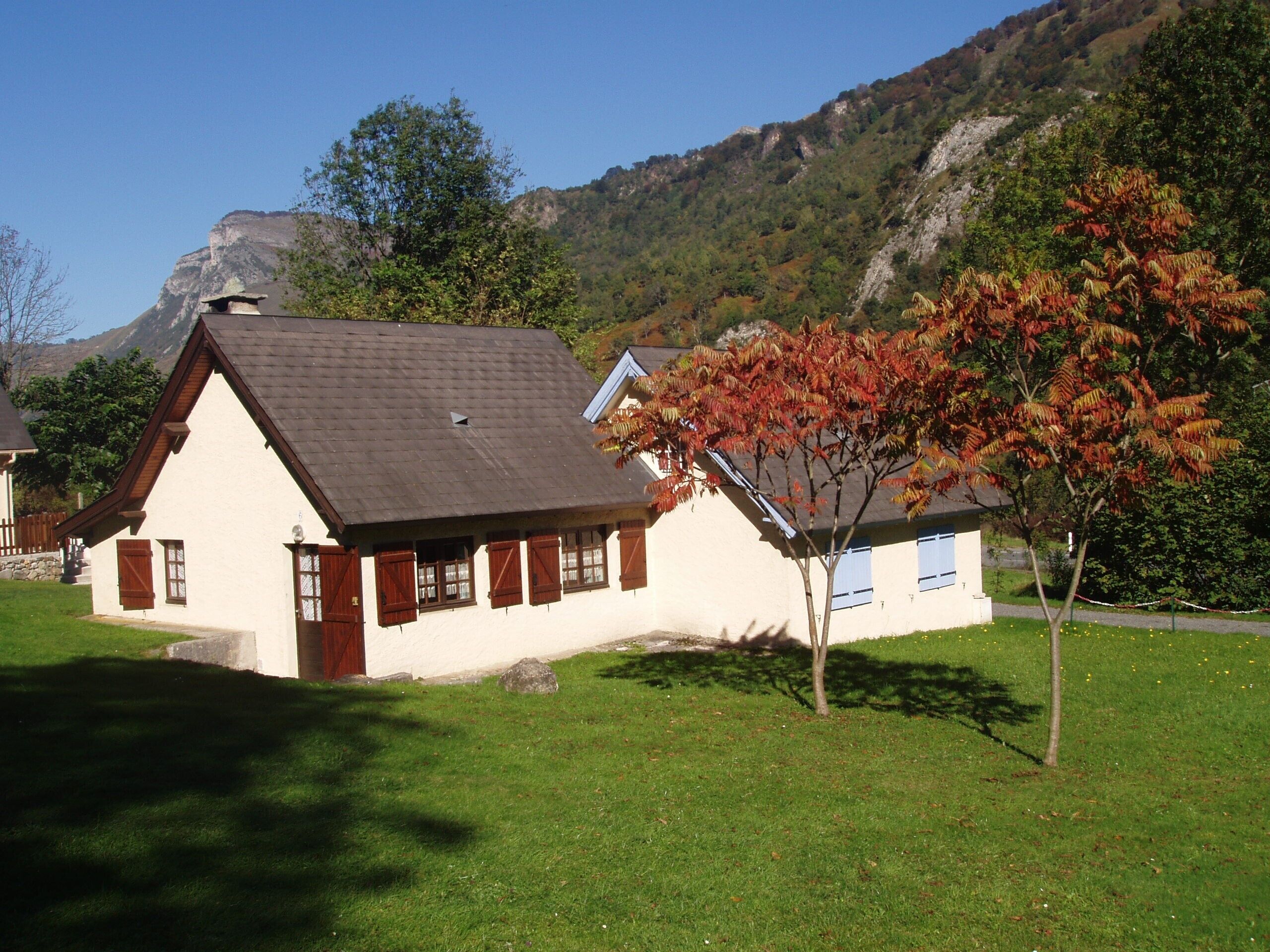 A traditional chalet with a sloped roof, a small porch, and a well-maintained lawn.