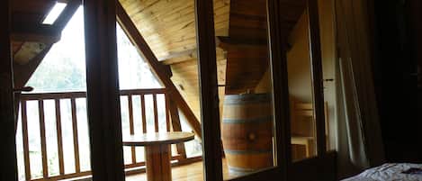 A room with a wooden ceiling, a large window, and a wooden barrel.