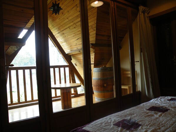 A room with a wooden ceiling, a large window, and a wooden barrel.