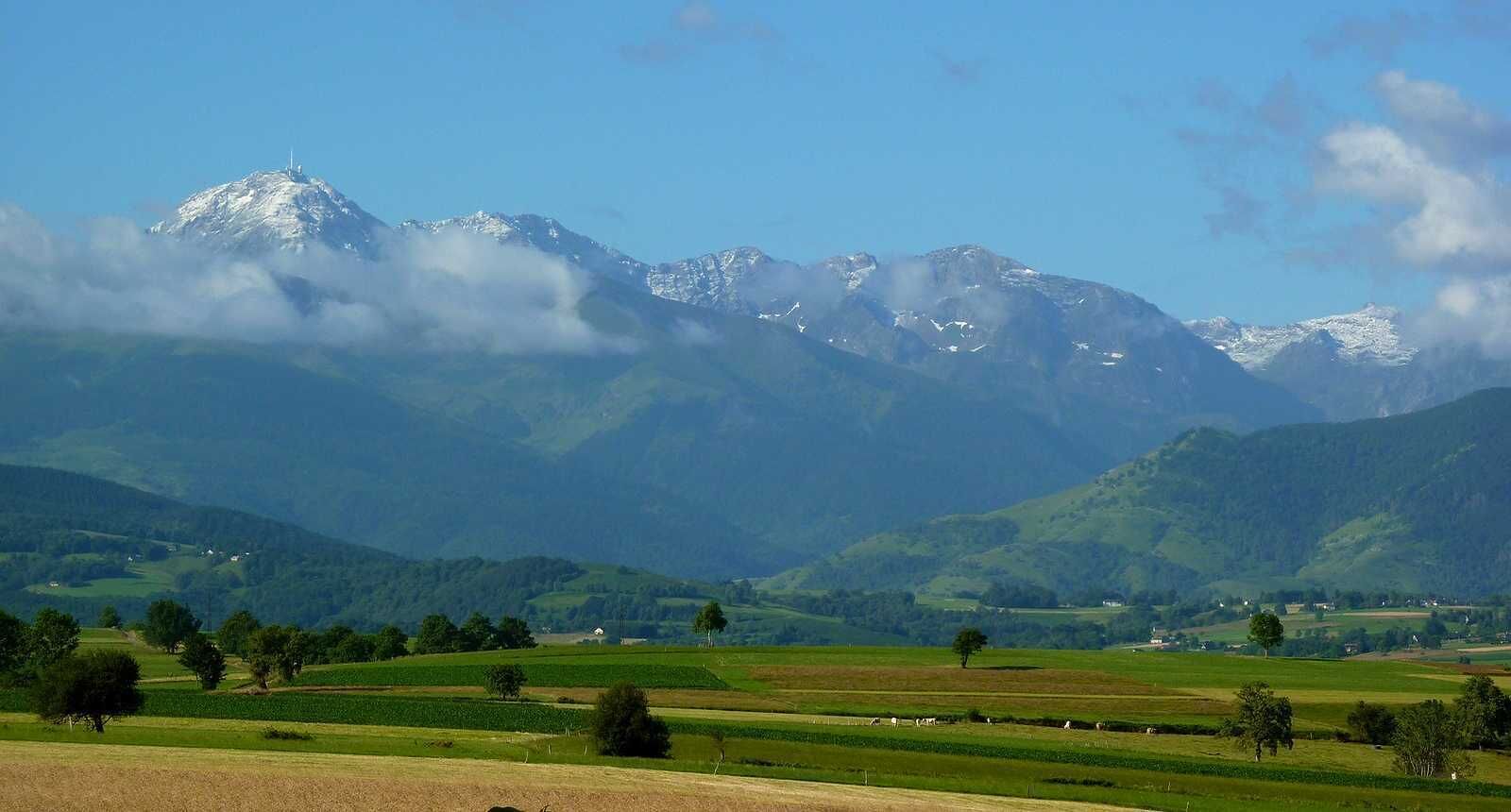 Un paisaje montañoso con campos y árboles dispersos.