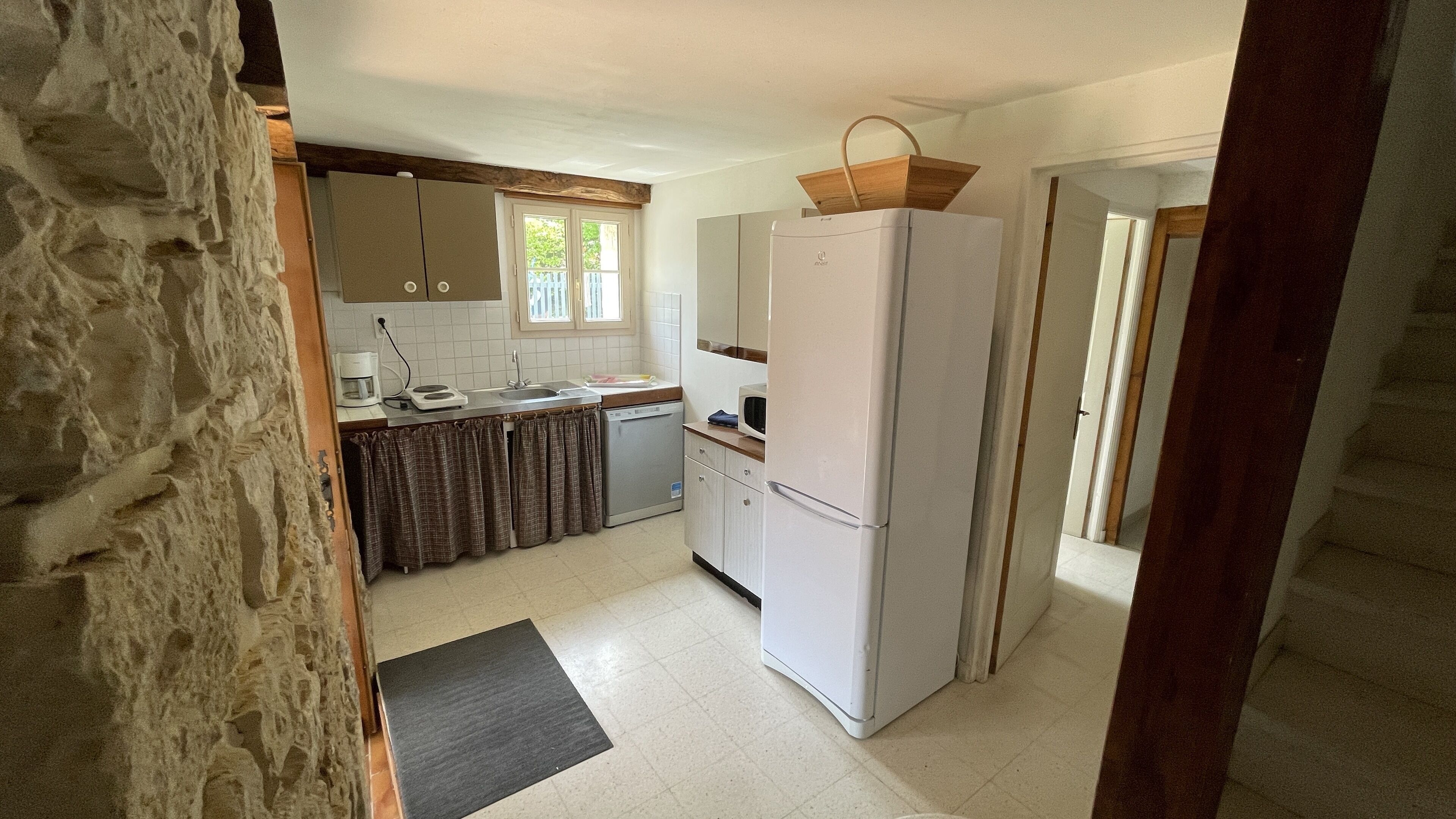 A compact kitchen with white cabinets, a white refrigerator, a microwave, and a small sink.