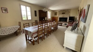 A dining area with a long table and chairs, a fireplace, and a television. - House with private swimming pool, in the heart of south-west (Thézac)