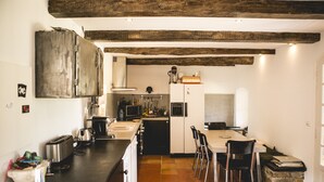 Une cuisine compacte dotée d’un îlot central, d’un coin repas avec des chaises et d’un comptoir en pierre.