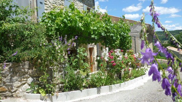 Un edificio de piedra con jardín delantero, adornado con diversas plantas y flores.