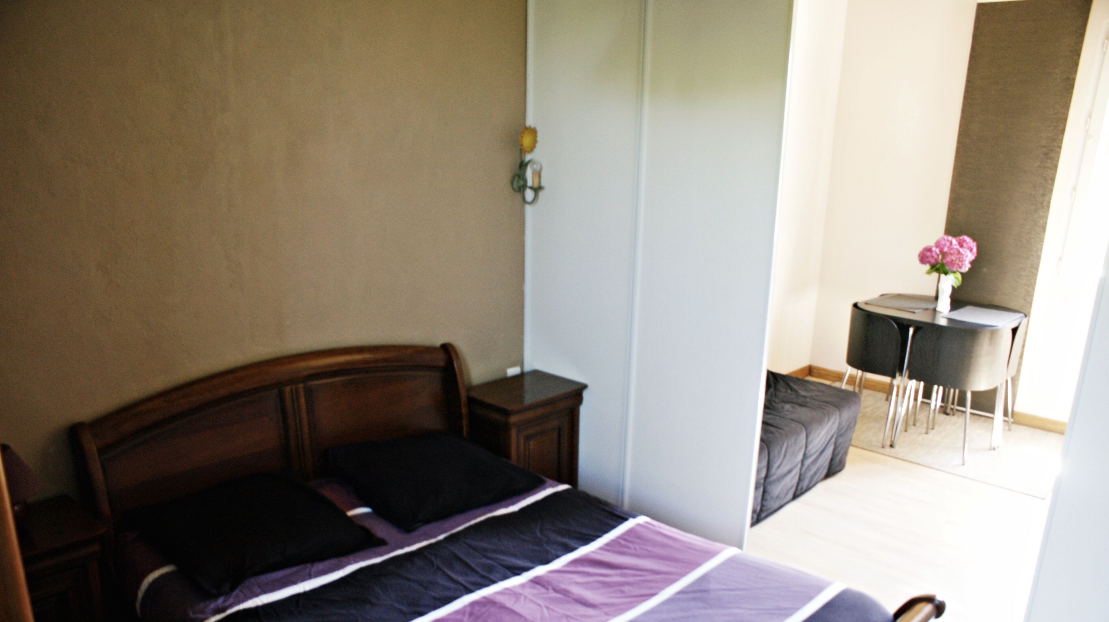A bedroom with a bed, bedside table, and a small desk with a chair.