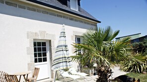A building with a stone facade, a window, and a striped umbrella. - Apartment quiet, rural setting not far from the sandy beaches (Plonéour-Lanvern)