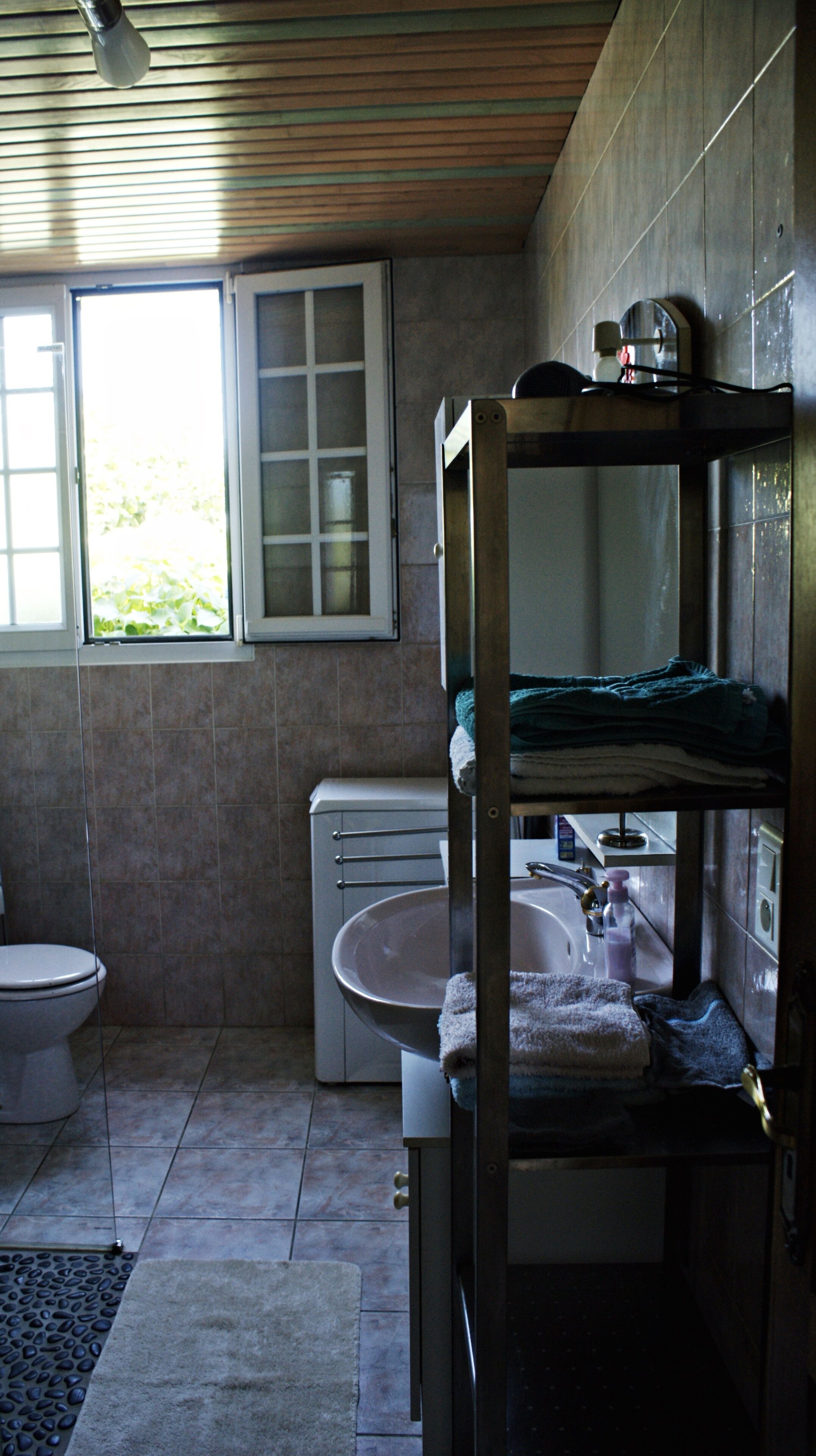 Une petite salle de bain comprenant des toilettes, un lavabo et une petite fenêtre.