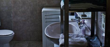 Une petite salle de bain comprenant des toilettes, un lavabo et une petite fenêtre.