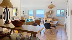 Un comedor espacioso con vista al mar, un balcón con mobiliario exterior y un diseño interior moderno.