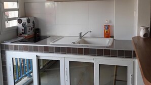 A modern kitchen with a sink, cabinets, and a television. - Diamond Beachfront Studio (Le Diamant)