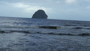 A large rock formation in the ocean with waves approaching. - Diamond Beachfront Studio (Le Diamant)