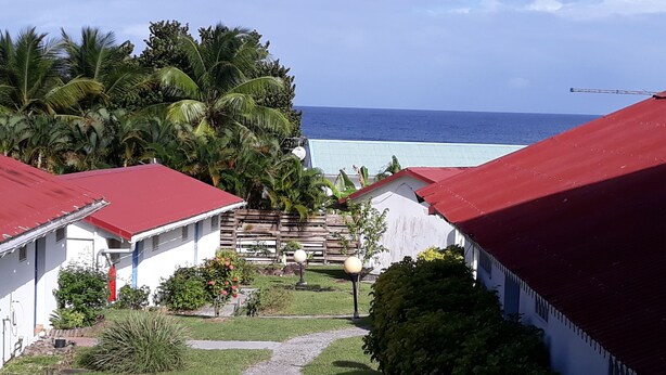 A coastal property with red-roofed buildings, a pathway leading to a beach, and lush greenery. - Diamond Beachfront Studio (Le Diamant)