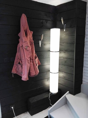 A bathroom with a black wooden wall, a pink robe hanging on the wall, and a vertical light fixture.