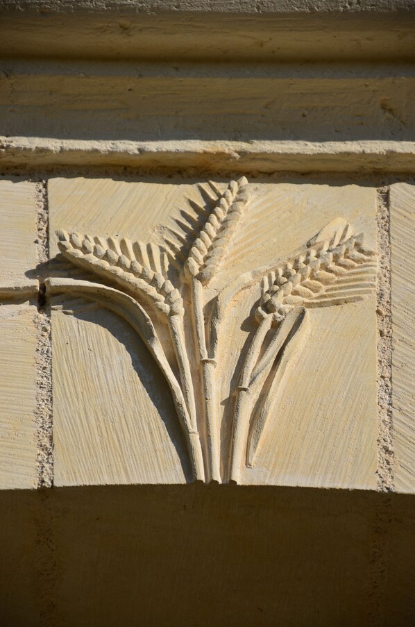 A detailed architectural carving of wheat sheaves on a building facade. - peaceful farmhouse surrounded by fields and woods, renovated comfort (Villedieu-Le-Château)