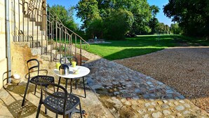 Un patio con una mesa y sillas, un sendero de piedra y una zona ajardinada con árboles.