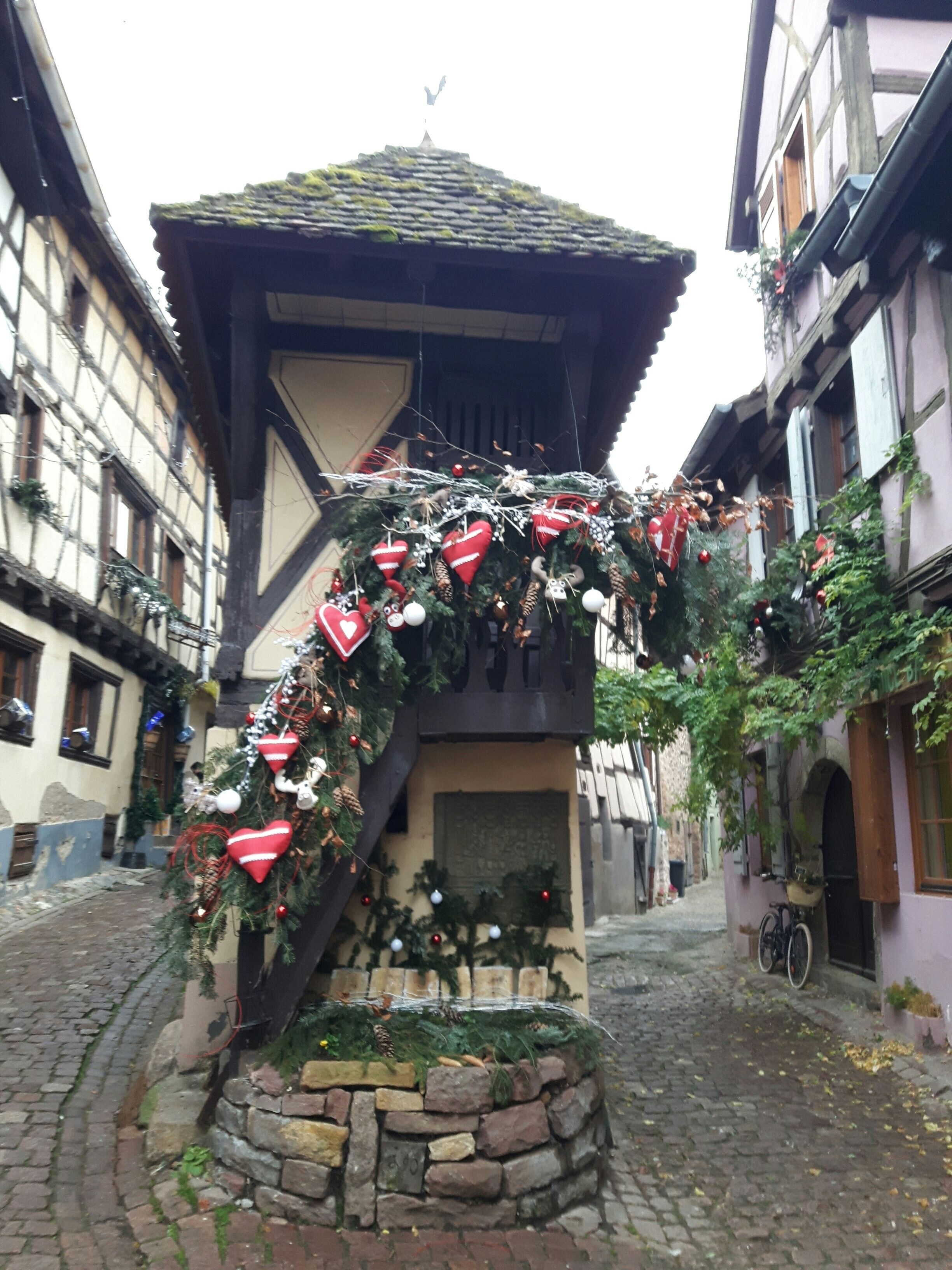 A traditional European building with a stone staircase leading to a wooden door, surrounded by cobblestone streets and neighboring buildings.