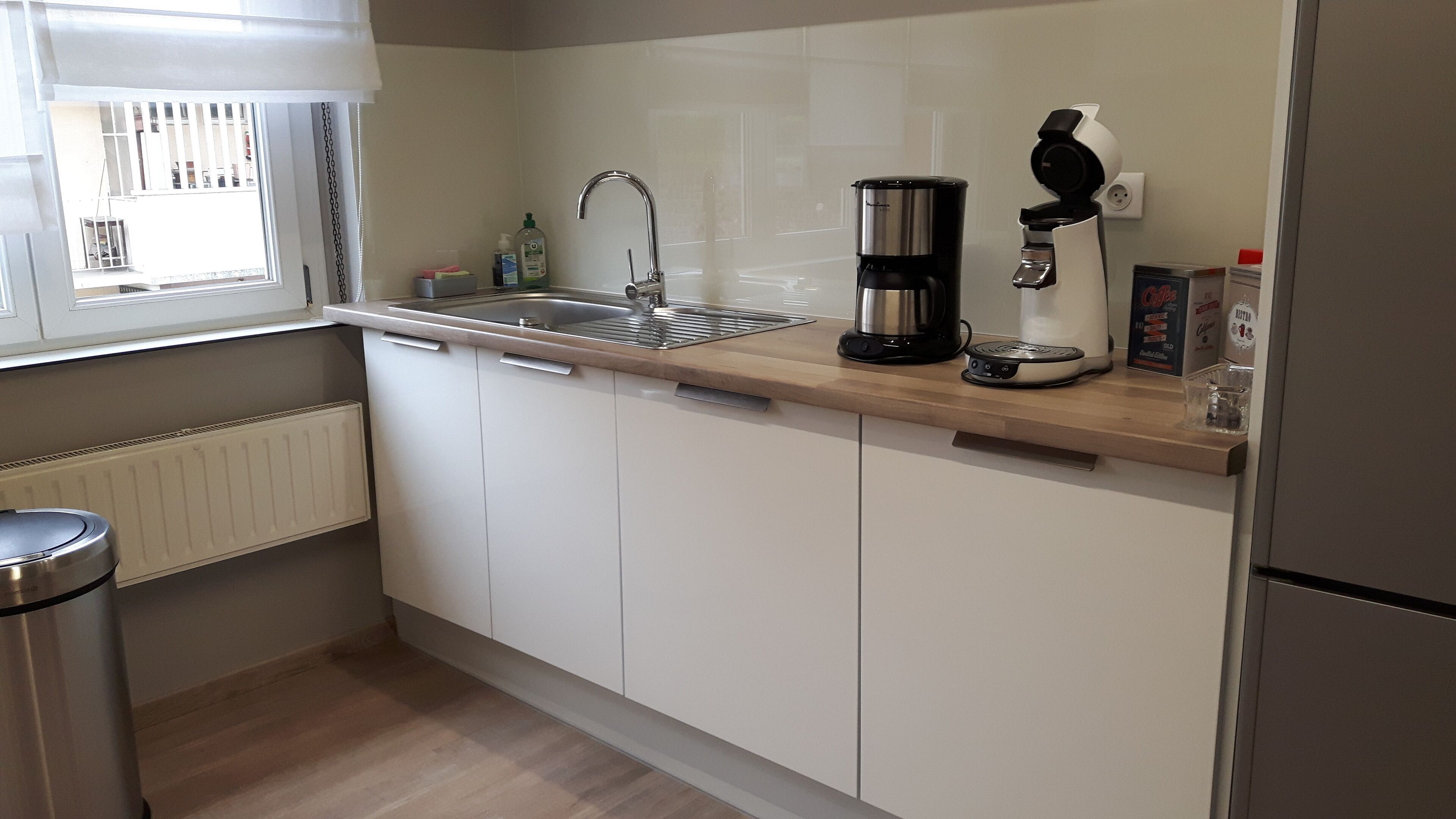 A kitchen with a stainless steel sink, a coffee maker, and a toaster.