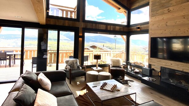 A spacious living room with a large sofa, a coffee table, and a fireplace. There are large windows offering a view of the mountains. - Chalet Aguila 5***** (NEW) sleeps 12 - XXL. jacuzzi and panoramic sauna (Bolquère)