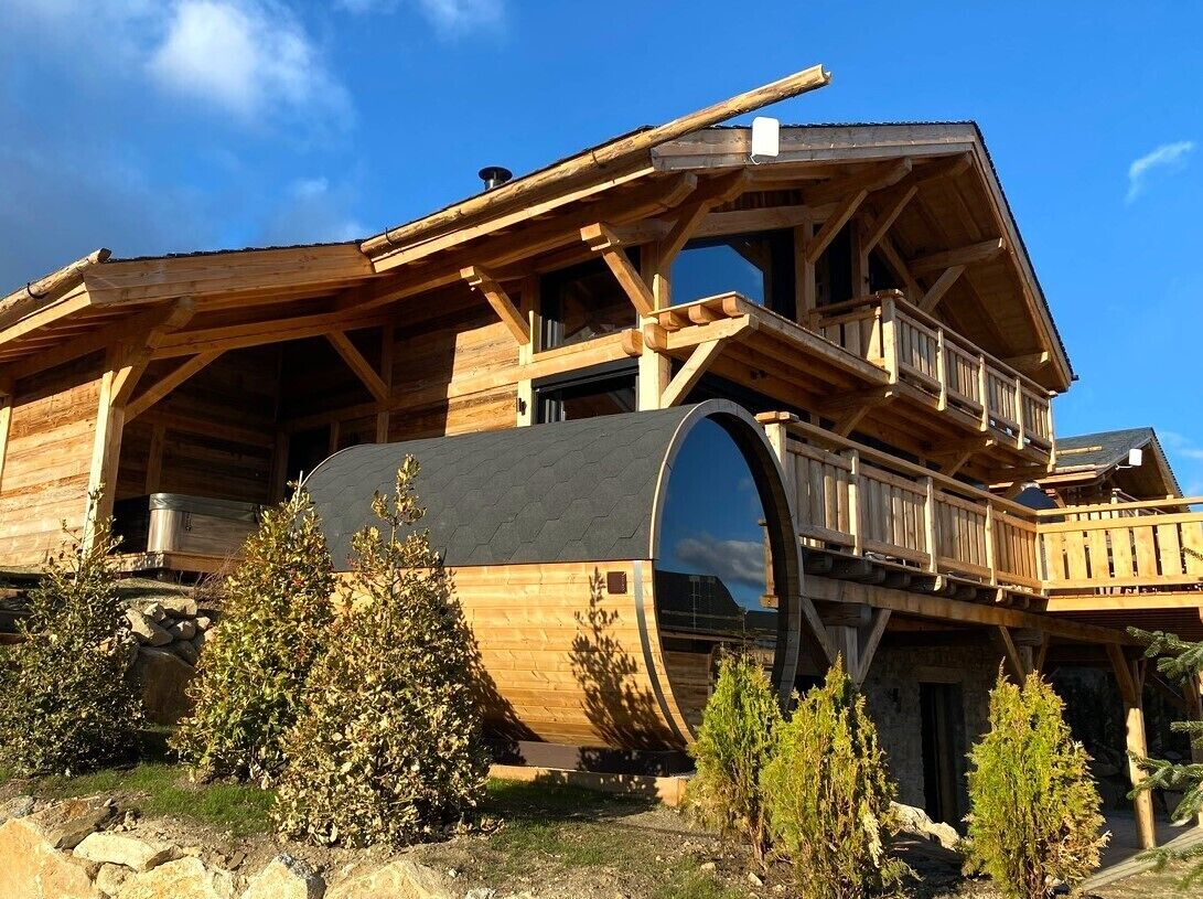 A wooden cabin with a large circular window, a balcony, and a stone foundation.