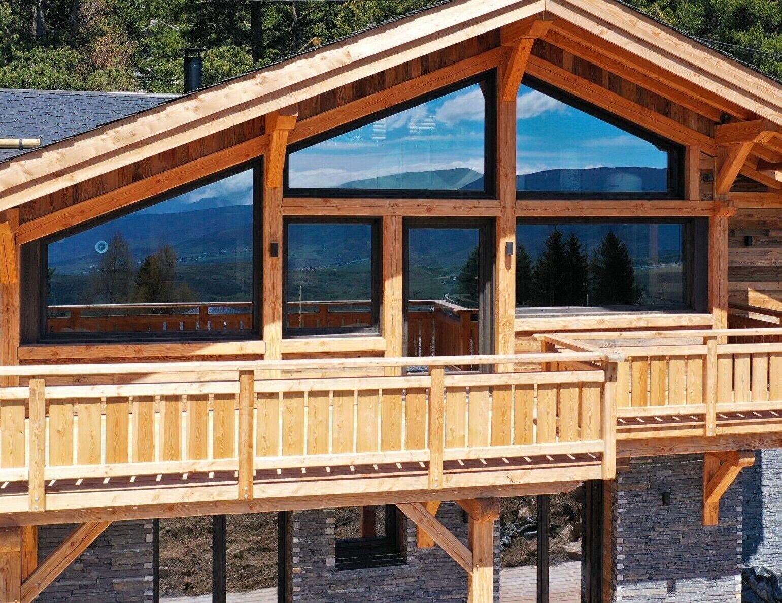 A wooden cabin with large windows and a deck.