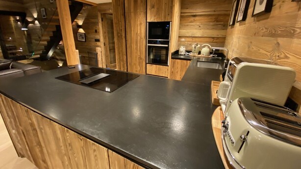 Une cuisine moderne agrémentée de touches de bois, dotée d’un plan de travail noir et d’un grille-pain vintage.