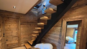 A wooden interior with a staircase, a polar bear sculpture, and a bed visible through an open doorway. - Chalet Aguila 5***** (NEW) sleeps 12 - XXL. jacuzzi and panoramic sauna (Bolquère)