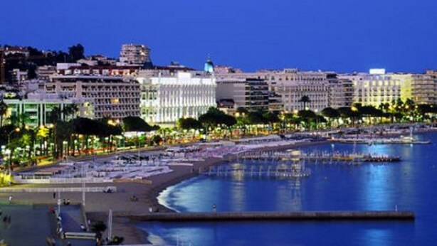 Un paysage urbain côtier avec une plage, une promenade et des bâtiments donnant sur le front de mer.