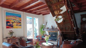 Un salon chaleureux avec des canapés en cuir, une cheminée et un tableau représentant un paysage.