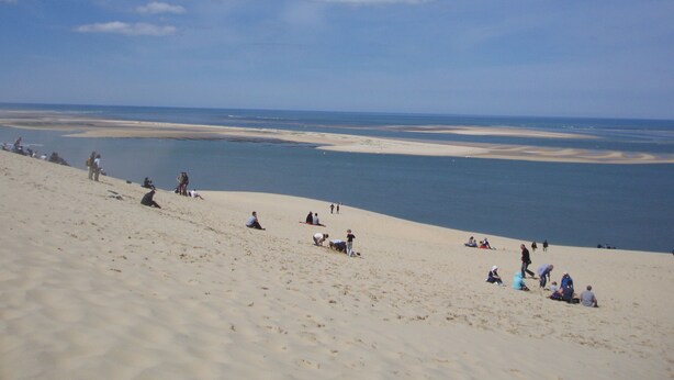 Une plage de sable où des gens prennent des bains de soleil et se détendent.