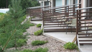 A wooden deck with metal railings, a chair, and a small plant. - Huoneistohotelli Jääskän Loma (Kauhava)