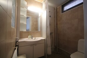 Un baño con lavamanos, espejo, ducha e inodoro.
