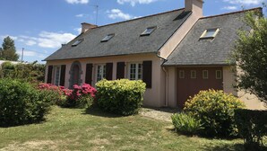 Una casa de dos pisos con techo inclinado, varias ventanas y una chimenea.