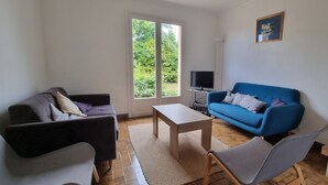Una sala de estar con un sofá, un sofá azul, un televisor y una chimenea.
