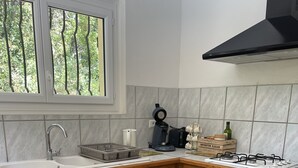 A kitchen with wooden cabinets, a gas stove, a coffee maker, and a wicker basket labeled "cuisine" on the table. - Riverfront house with pool at the foot of the Cascades du Sautadet (La Roque-Sur-Cèze)