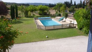 A rectangular swimming pool with a wooden deck and a slide, surrounded by a fence. - furnished studio overlooking the luberon (Lagnes)