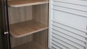 Una estantería de madera con tres repisas abiertas y un radiador blanco.