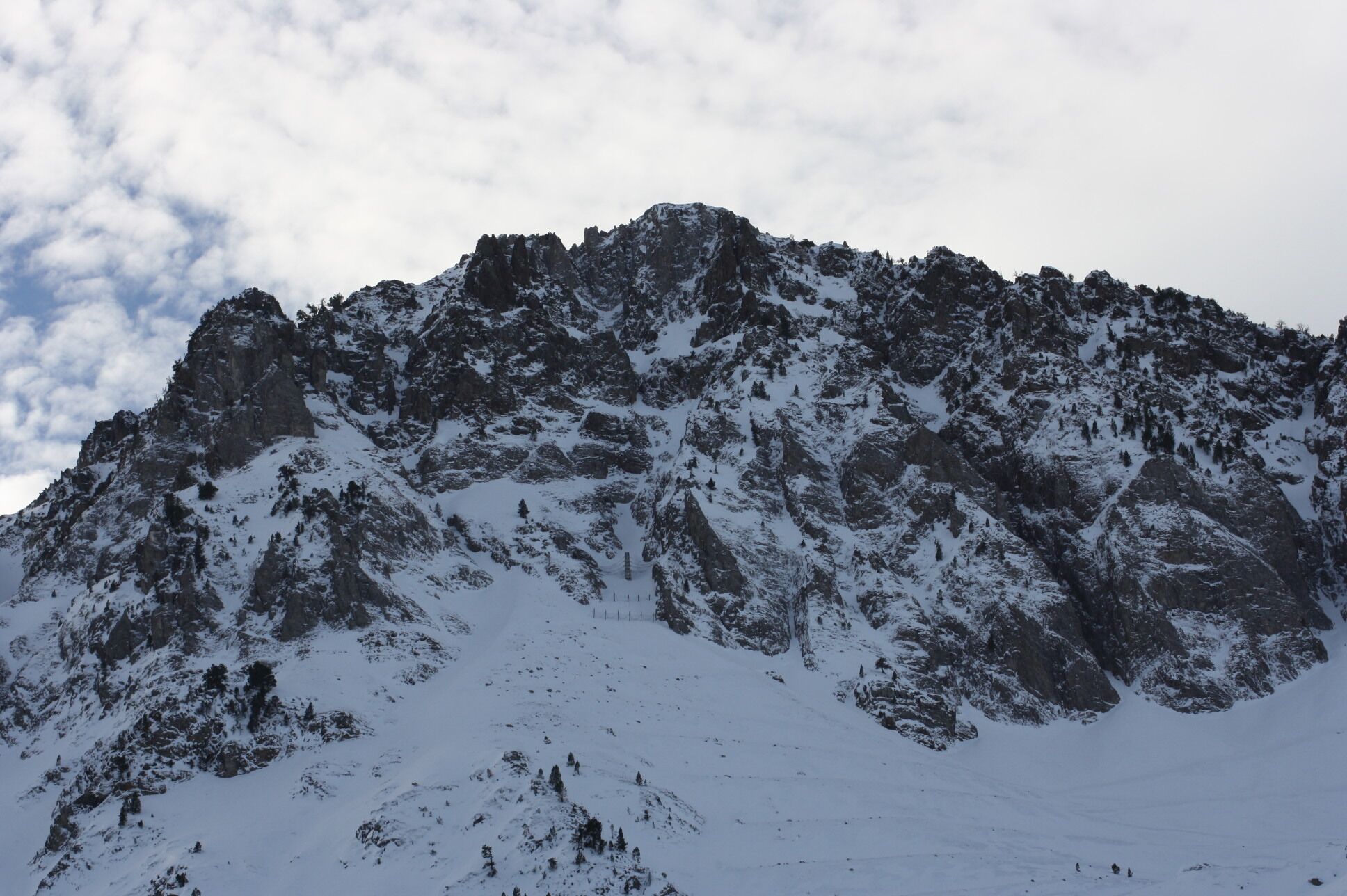 A snow-covered mountain with rugged terrain and sparse vegetation.