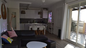 Ein modernes Wohnzimmer mit einer schwarzen Ledersofa, einem weißen Couchtisch und einem Essbereich mit weißem Tisch und Stühlen.