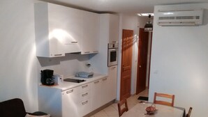 A compact living space with a kitchenette, a dining table with chairs, and a sofa. - 2-room apartment, new with terrace and sea view sleeping 2 to 4   (L'île-Rousse)