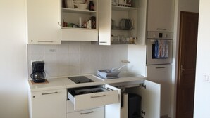 A compact kitchen with white cabinets, a coffee maker, a sink, and a built-in oven. - 2-room apartment, new with terrace and sea view sleeping 2 to 4   (L'île-Rousse)