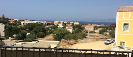 A residential area with houses, a clear blue sky, and a view of the sea.