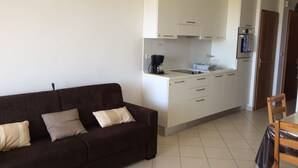 A compact living space with a sofa, kitchenette, and a dining area. - 2-room apartment, new with terrace and sea view sleeping 2 to 4   (L'île-Rousse)