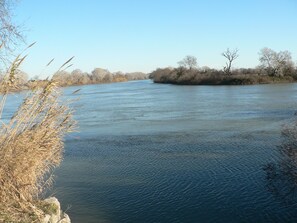 Un río de aguas tranquilas, rodeado de hierba seca y árboles.