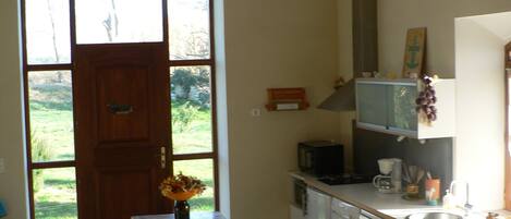 A kitchen with a wooden bench, a sink, and a window overlooking a garden.