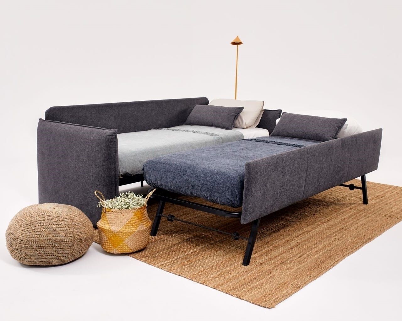 Et moderne sofasæt med tilhørende skammel, en vævet puf og en dekorativ kurv.
