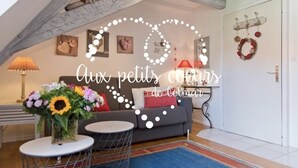 A cozy living room with a grey sofa, a round coffee table, and a floral arrangement. - Wonderful apartment in the heart of Little Venice (Colmar)