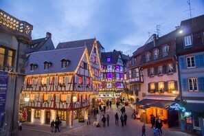 Una piazza tradizionale europea con edifici storici, un mercato centrale e decorazioni festive.