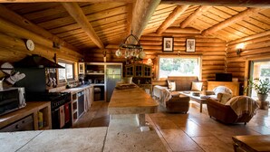 Een rustiek houten huisje met een keuken, eethoek en woonkamer.