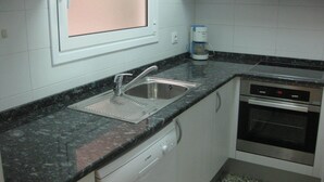 Una cocina con un lavamanos de acero inoxidable, un lavavajillas Bosch, una cafetera y un horno.