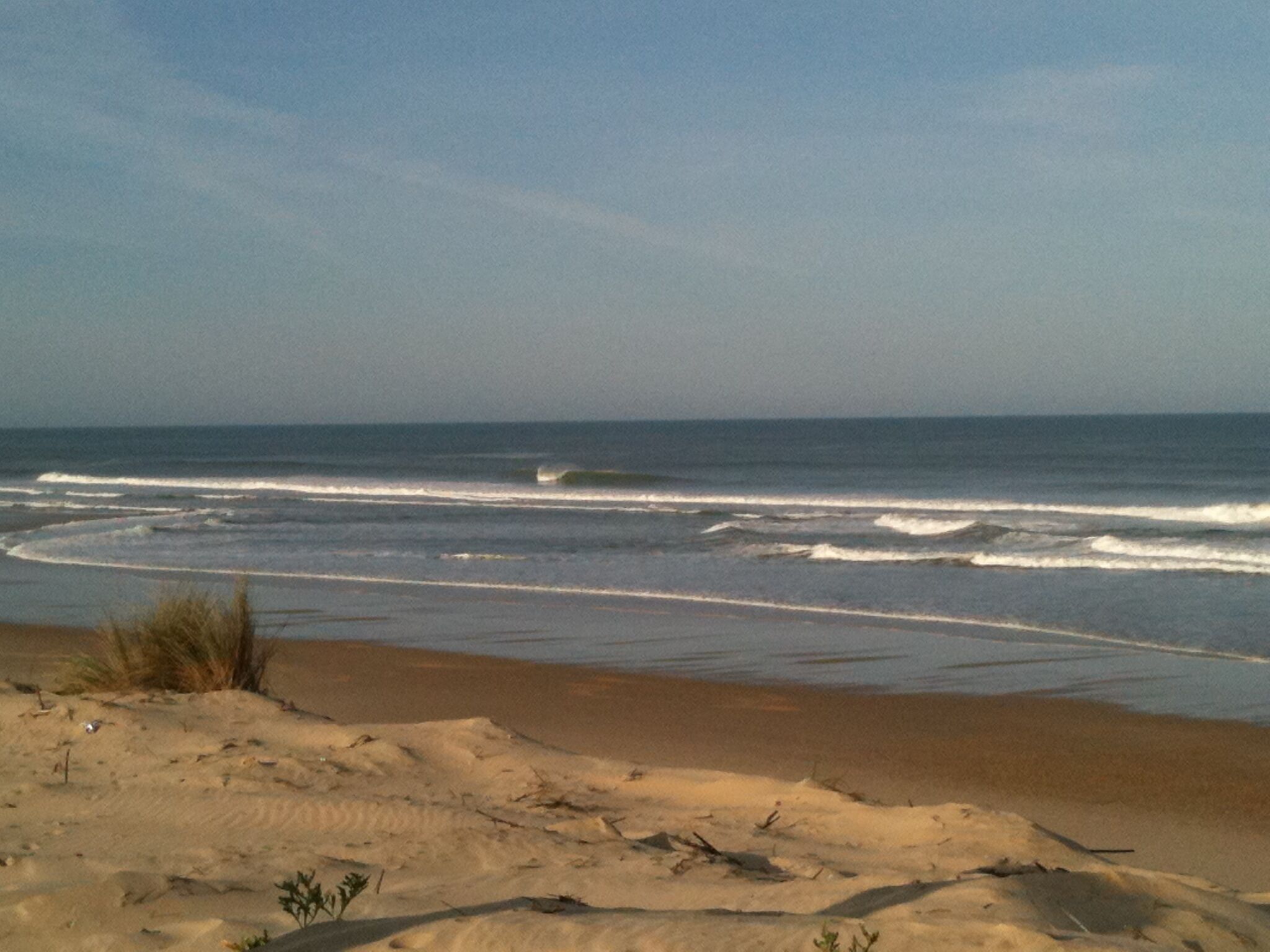 A beach with sand dunes and ocean waves.